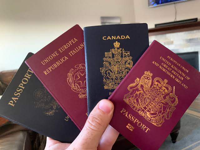 A hand holding several passports